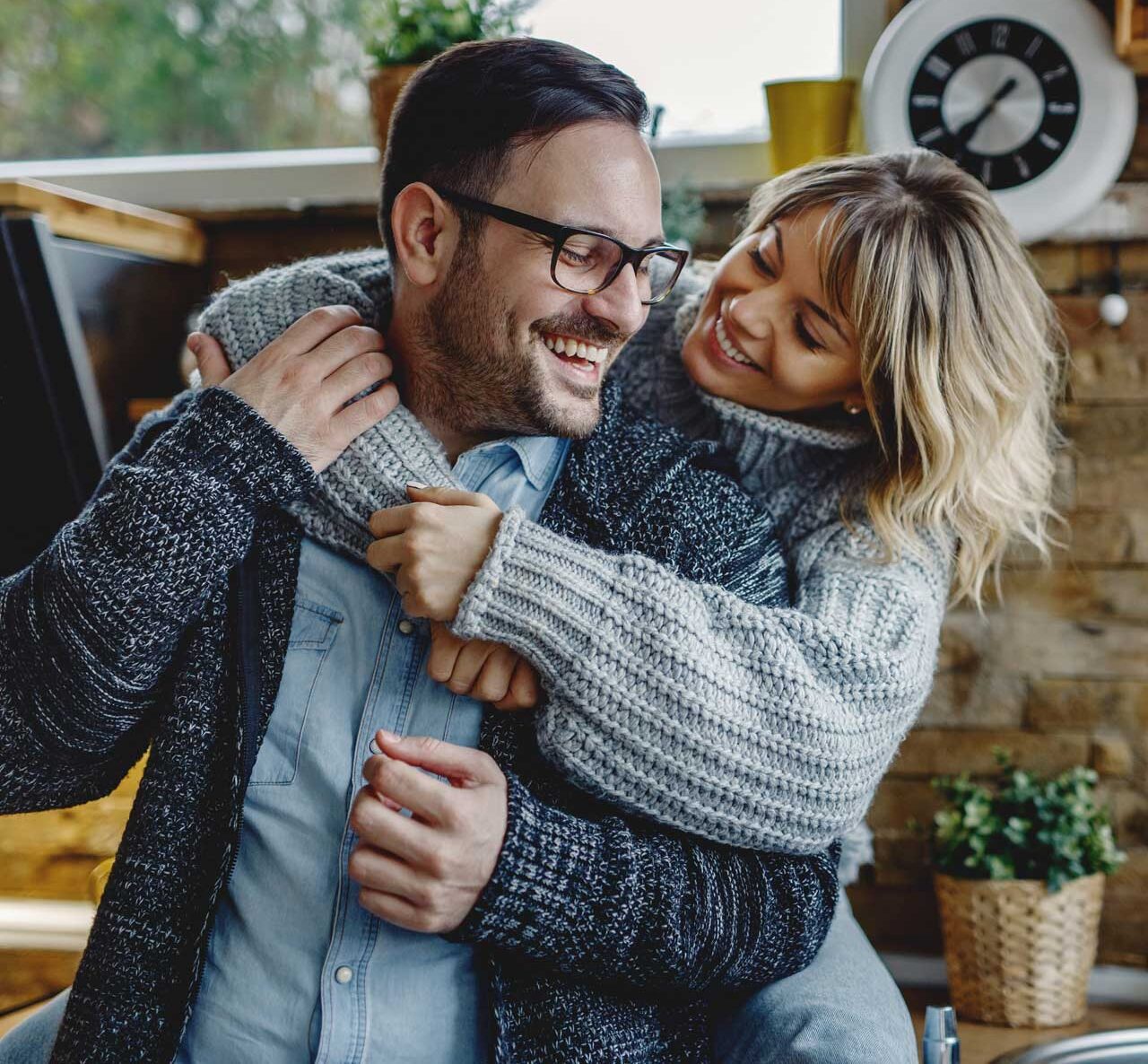 Success & Wellbeing Homepage Premarital & commitment counseling Offers Telehealth in New York, Massachusetts & Maine image of couple women embracing husband in kitchen