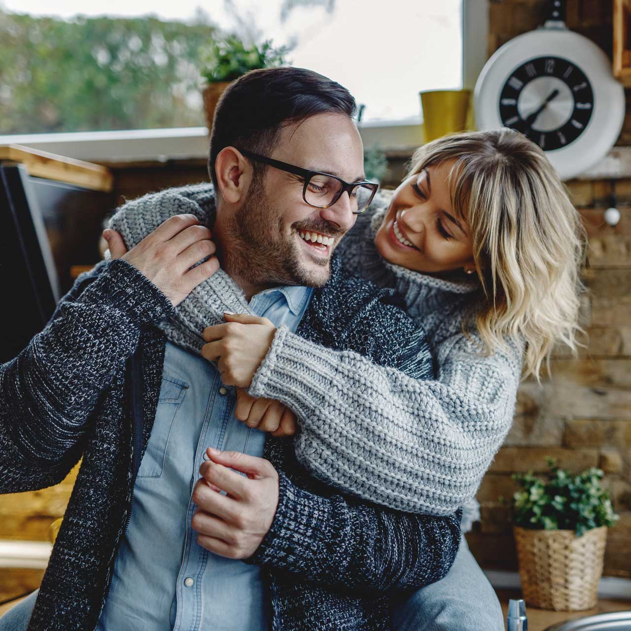 Success & Wellbeing Homepage Premarital & commitment counseling Offers Telehealth in New York, Massachusetts & Maine image of couple women embracing husband in kitchen