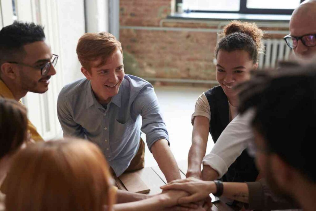 A diverse group of people sitting together outdoors, smiling and connected, symbolizing the supportive community aspect of group therapy.