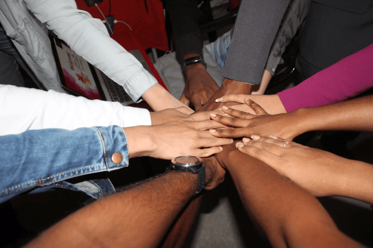 Diverse group of people joining hands together in unity, symbolizing support, trust, and teamwork."