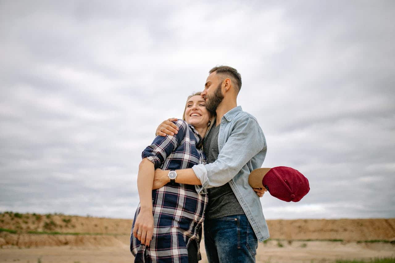 Couple hugging affectionately in an open outdoor setting, representing emotional closeness and support.