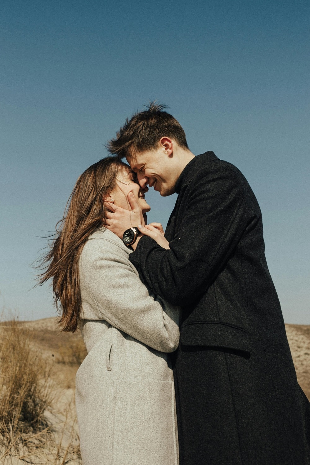 couple stands close in front of a natural landscape