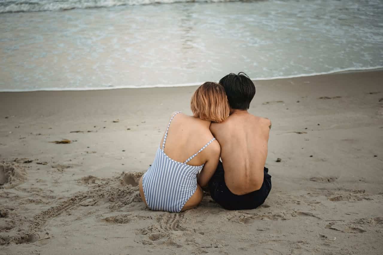 Couple sitting close together on a beach, reflecting emotional closeness and relationship healing through couples therapy.