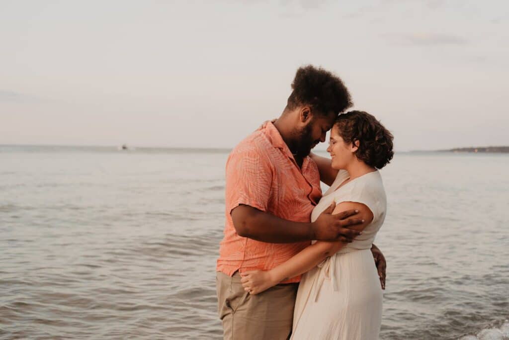 Couple embracing by the ocean representing connection and progress in couples counseling