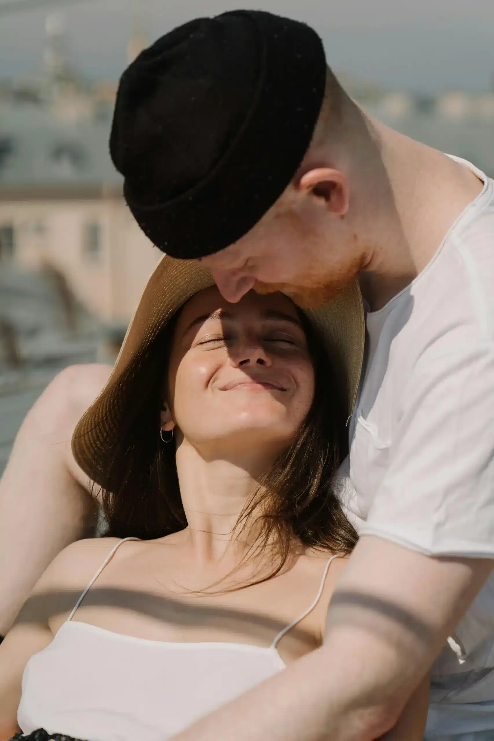 A couple standing on the beach with warm sunlight on their faces, sharing a calm moment and smiling at each other