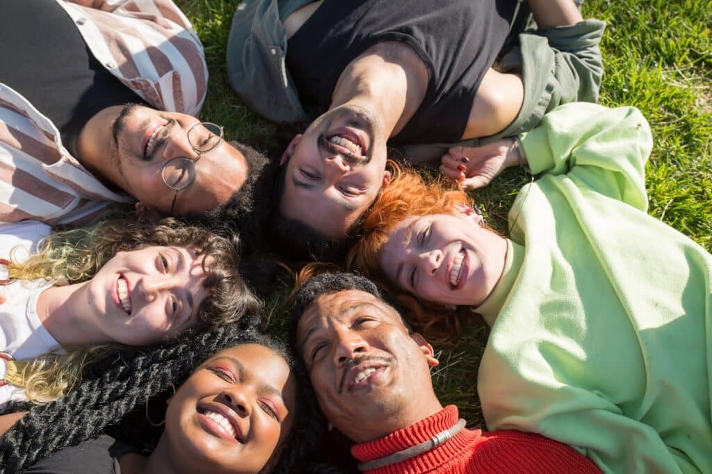 Diverse adults lying in a circle smiling, representing connection and support in group therapy