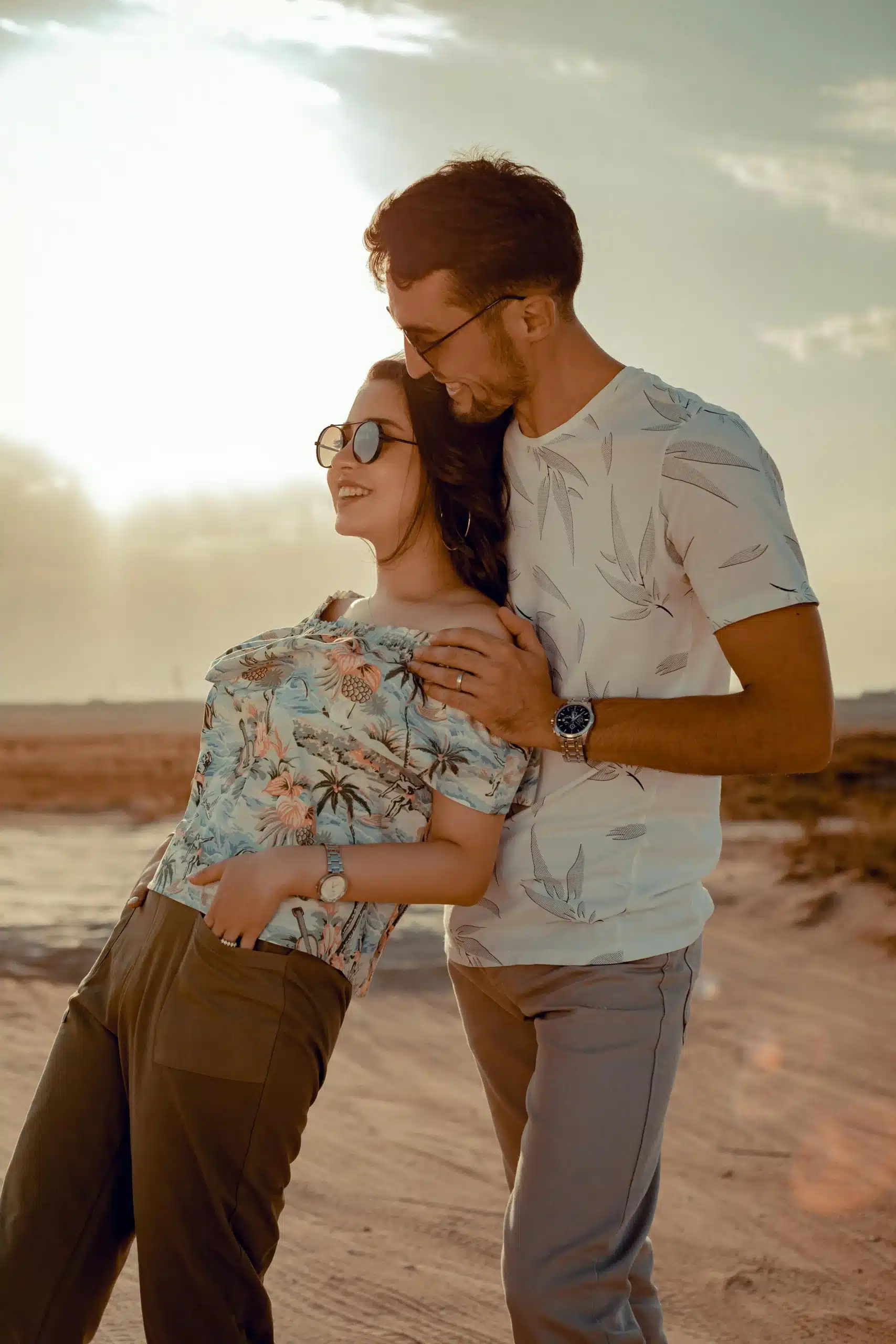  A woman leaning gently on her partner while walking along a beach, both smiling and enjoying a peaceful moment