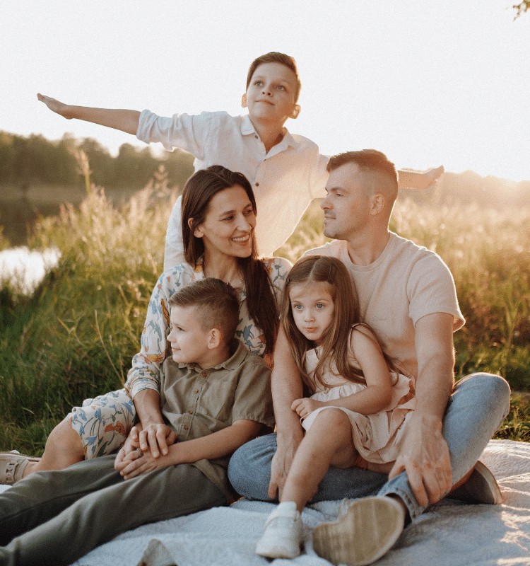 A family of five enjoying a picnic outdoors, smiling and connecting through shared time and meaningful moments.