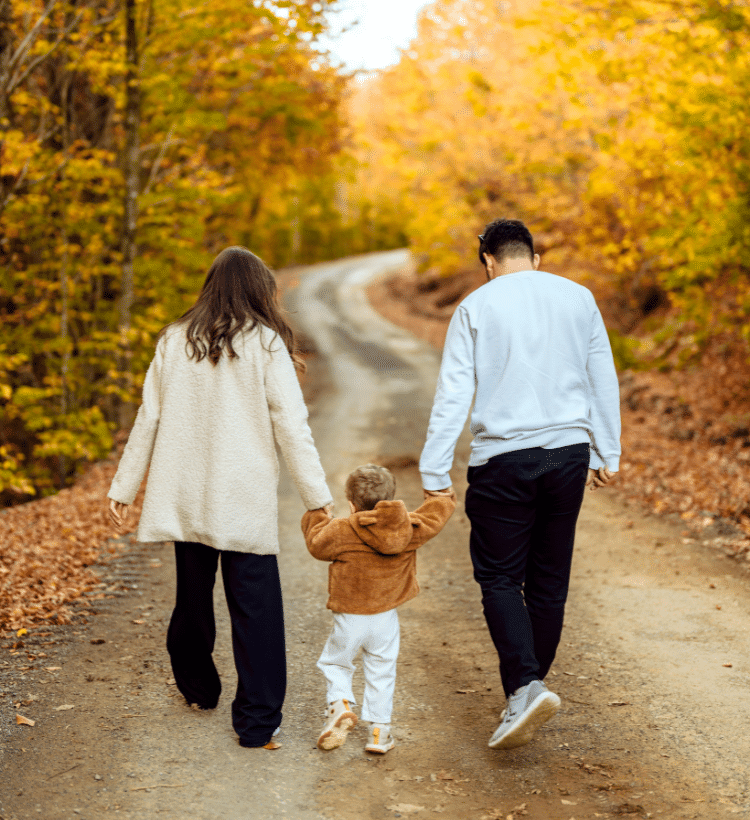 Two parents walking with their child between them symbolize guidance, support, and family unity in daily life.