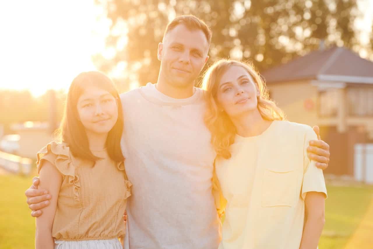 Family standing together outdoors smiling, representing connection and participation in family therapy