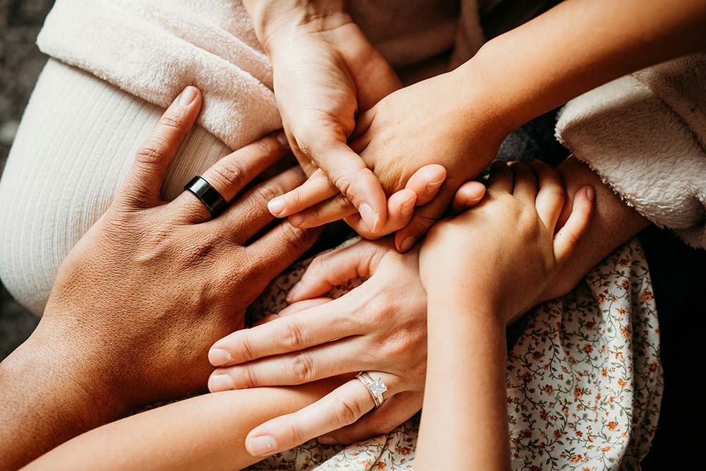 A group of people putting their hands together in a team gesture.