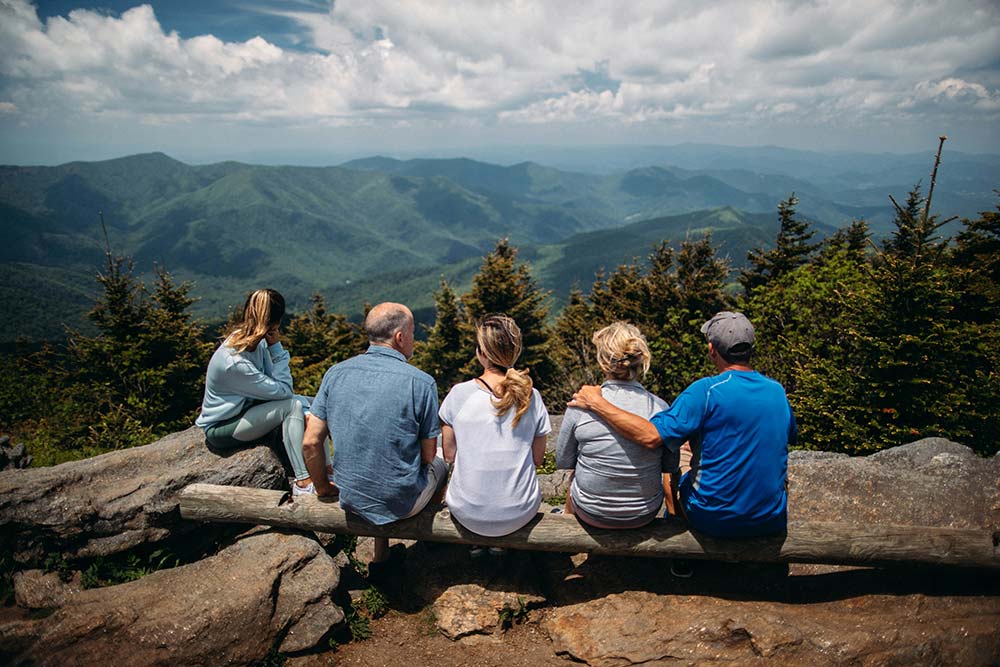 A group of people sitting on rocks overlooking a mountain view.