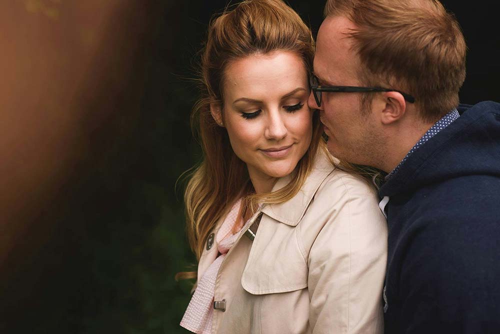 a man whispers to a woman outdoors