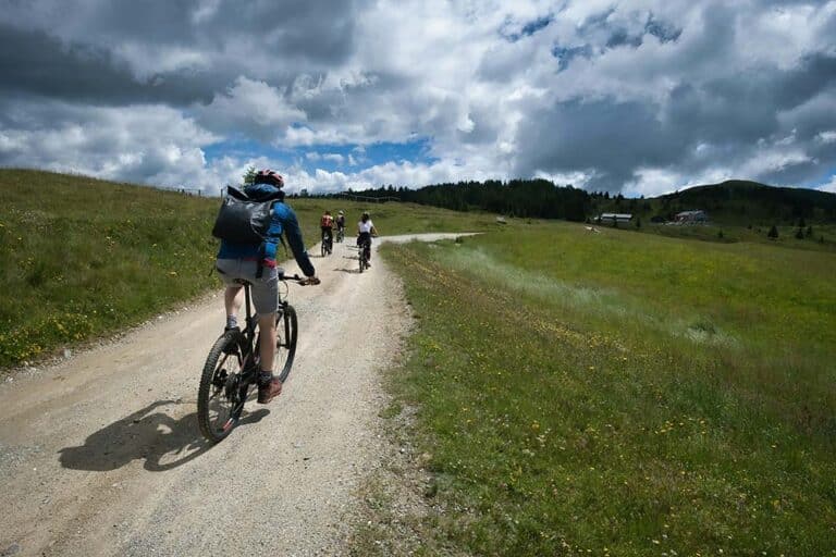 Cyclists riding on a dirt path through grassy hills