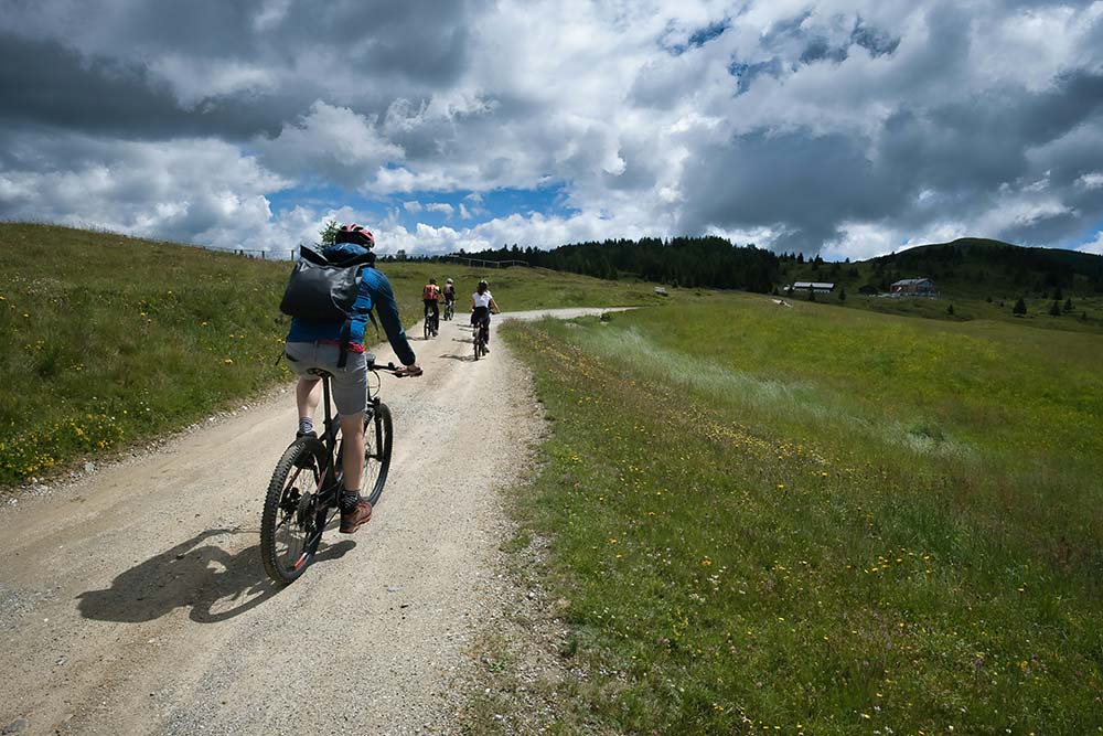 Cyclists riding on a dirt path through grassy hills